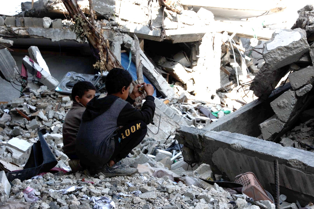 Des enfants sont assis au milieu des décombres des maisons détruites de leurs familles à Gaza.